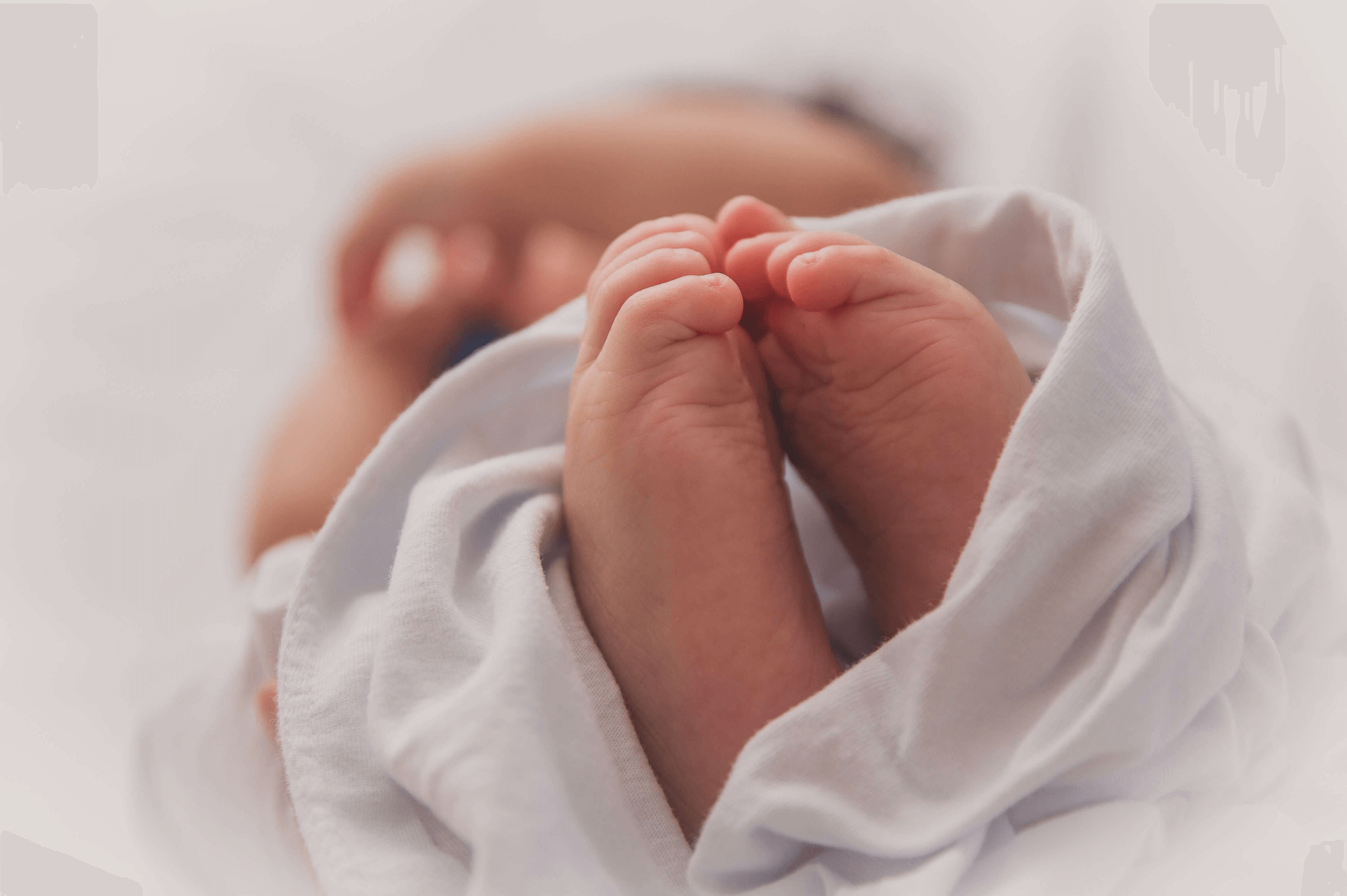 Newborn baby swaddled in blanket with toes to the camera