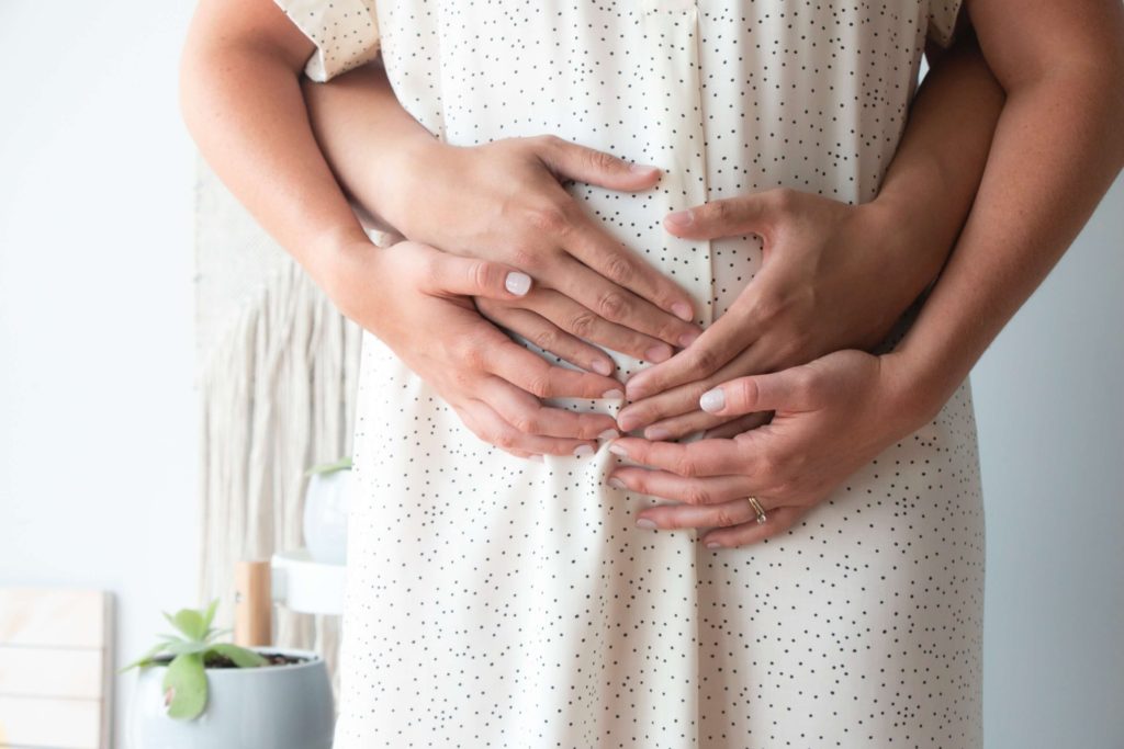 A pregnant mother and her husband holding her baby bump